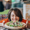 ‘Eat out to help out’ czyli niższe rachunki w restauracji Young pretty woman eating pizza at pizza bar